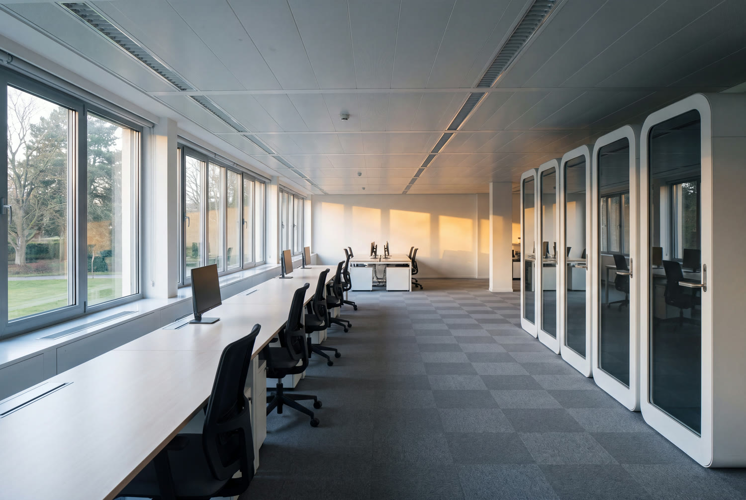 Grand plateau de bureaux impeccable au lever du jour à Woluwe, moquette aspirée et postes dégagés